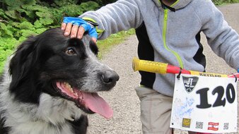 Eine Aufnahme eines Kindes mit Kinder-Fahrrad und Hund auf einem Schotterweg | © Haus Tannenblick