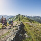 Eine Familie mit zwei Kindern wandert entlang eines Bergpfads | © saalbach.com - Mia Knoll